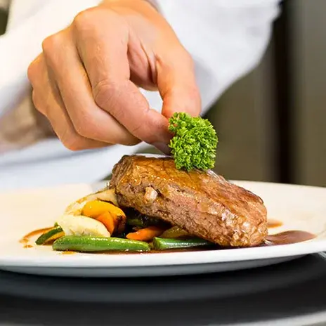Riverwalk Estates Chef Created Meals, chef garnishing a plate.