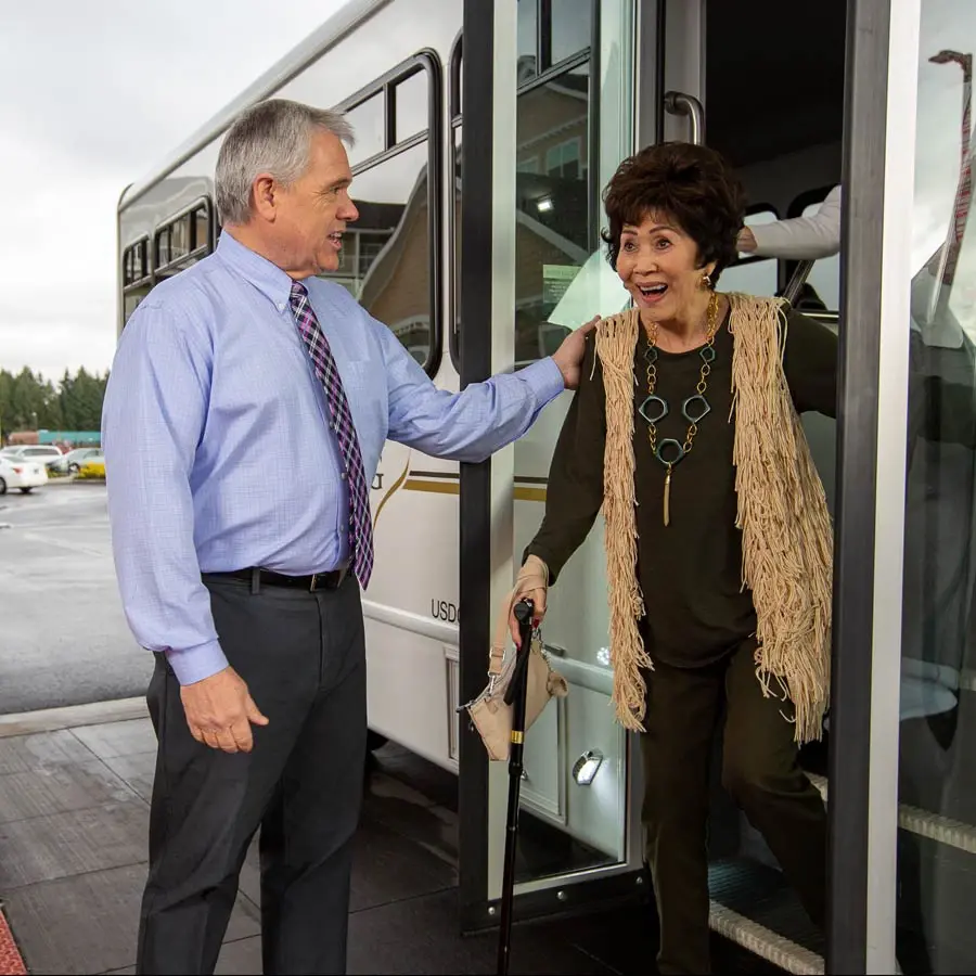 Riverwalk Estates man helping lady off bus
